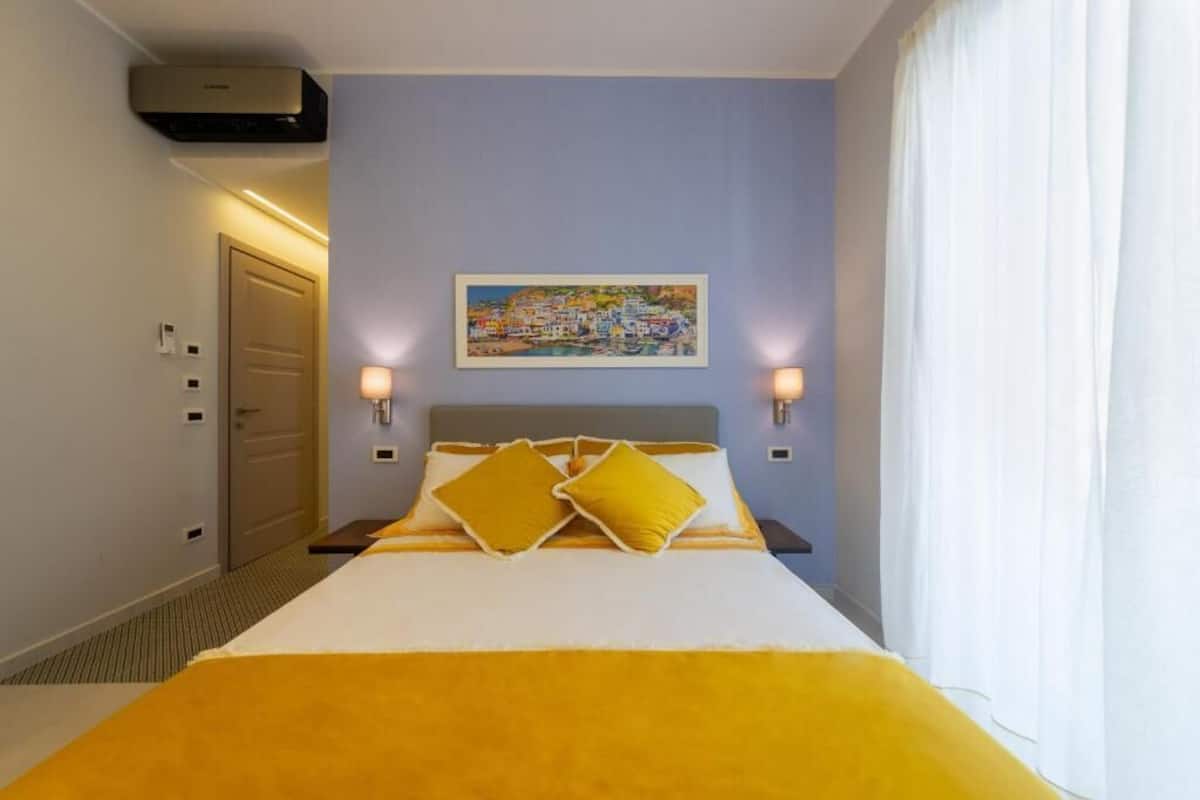 A hotel room with a bed, a painting on the wall, and a door.
