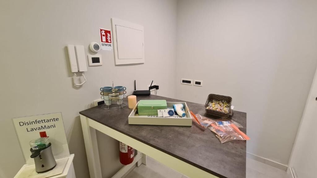 A room with a desk containing a tissue box, a tissue roll, a small trash bin, and a tray with tissues and a tissue box.