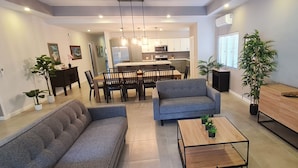 A modern living room with a sofa, a coffee table, a TV, and a wooden cabinet. - New spacious luxury 4-bedroom villa in gated development close to beaches. (Canaan)