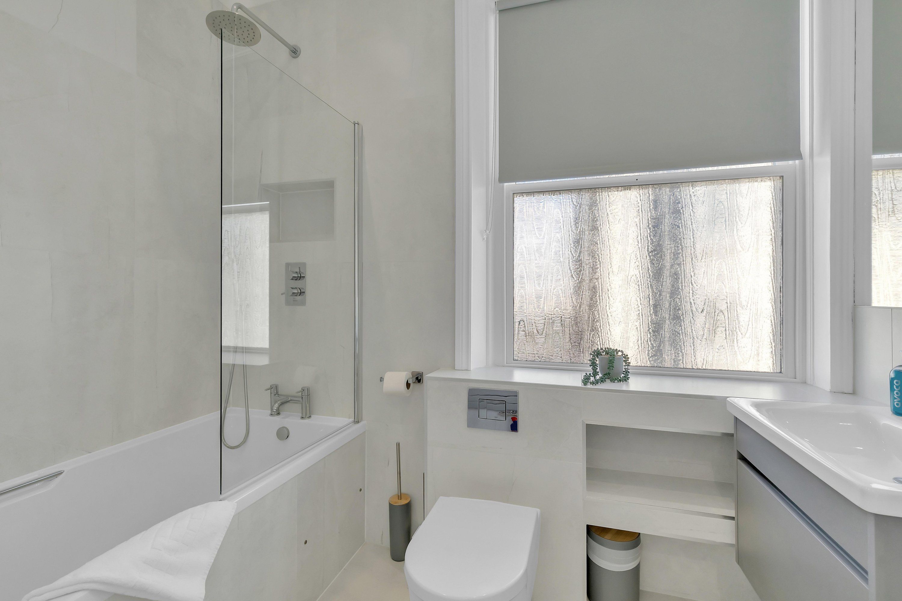 Un baño moderno con ducha envuelta en vidrio, inodoro y lavamanos.