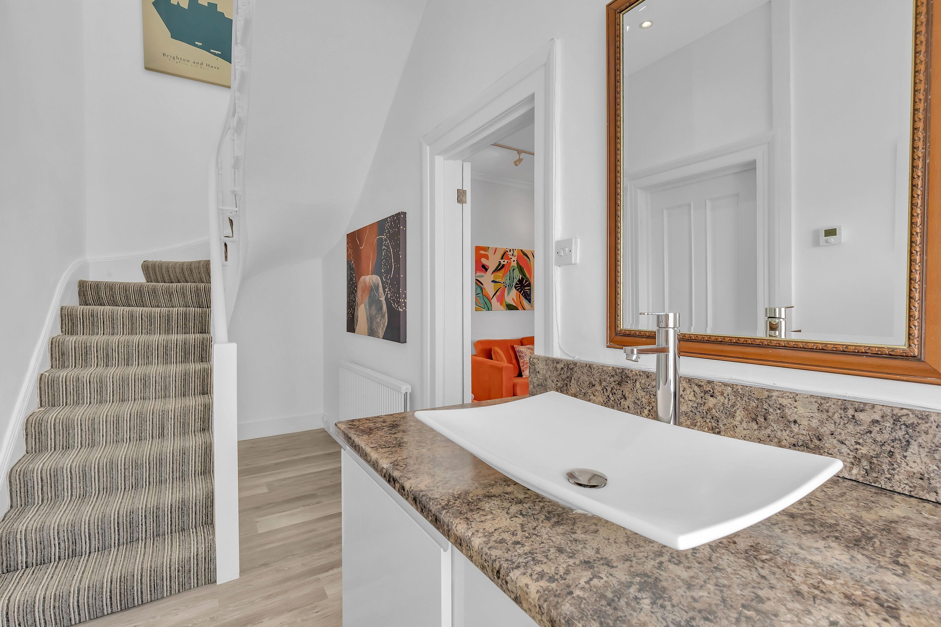 A modern bathroom with a white sink, granite countertop, and a large mirror.