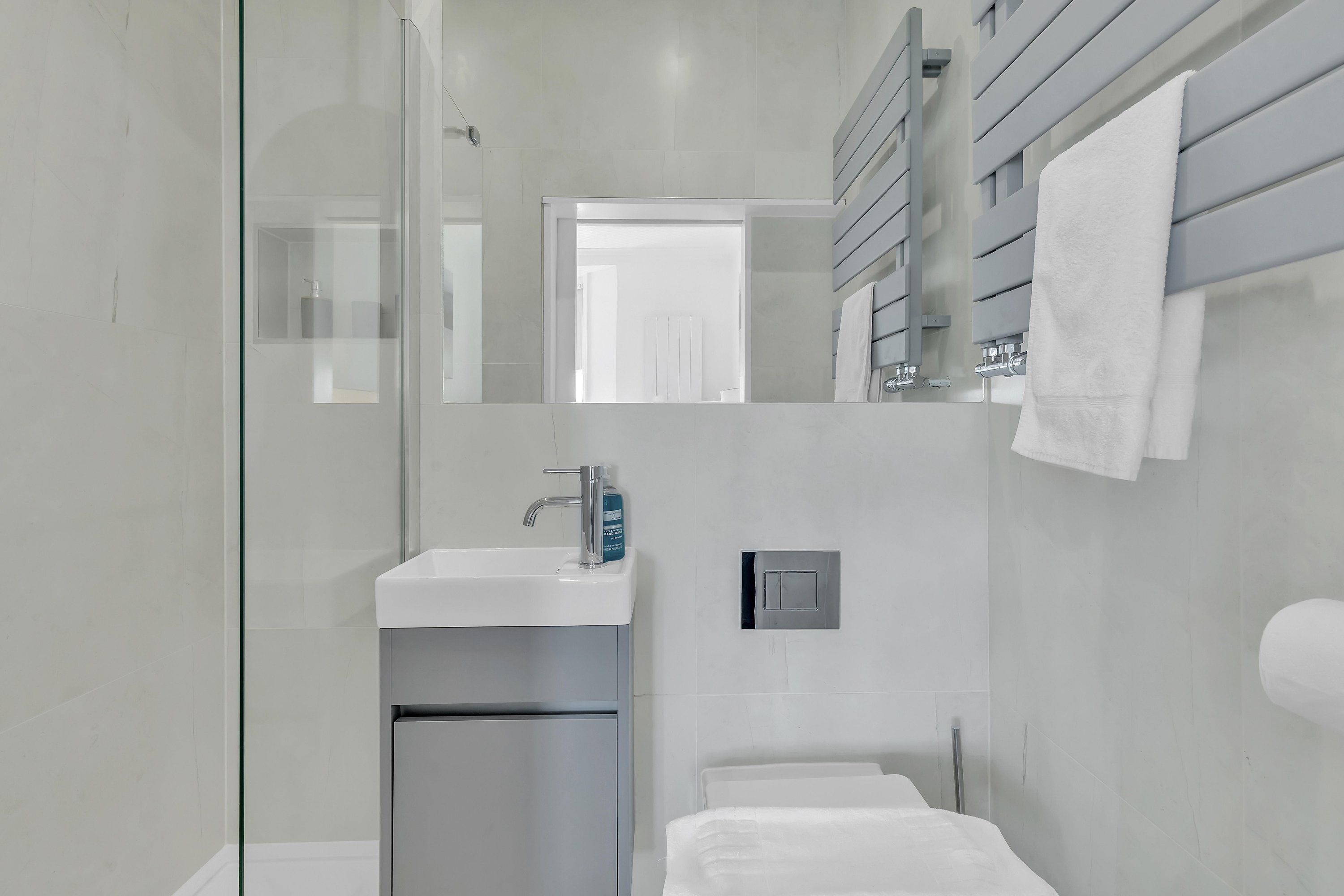 Ein modernes Badezimmer mit Duschkabine aus Glas, integriertem Waschbecken und Handtuchhalter.