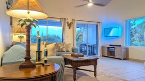Una sala de estar con un sofá, una mesa de centro, una lámpara y un televisor.