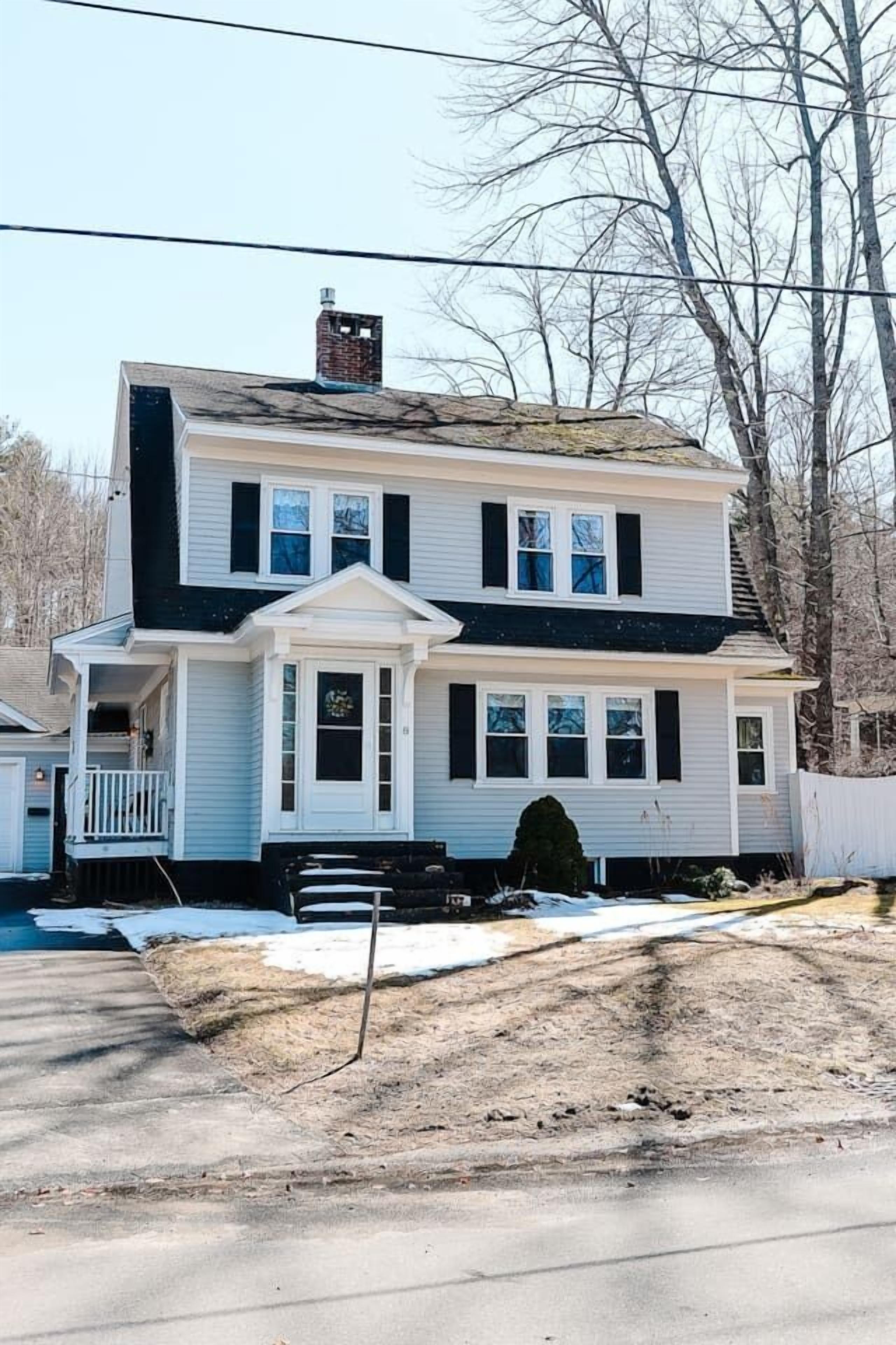 A two-story house with a front porch and a chimney.
