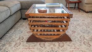 A rustic wooden coffee table with a glass top and a metal base, placed on a patterned carpet in a living room. - Dutch Retreat • Near Lakes • Walk Town (Bridgton)