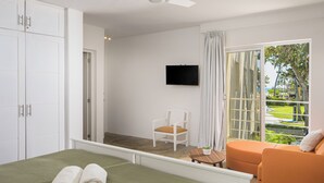 Une chambre à coucher avec un lit, une chaise, une télévision et un balcon offrant une vue.