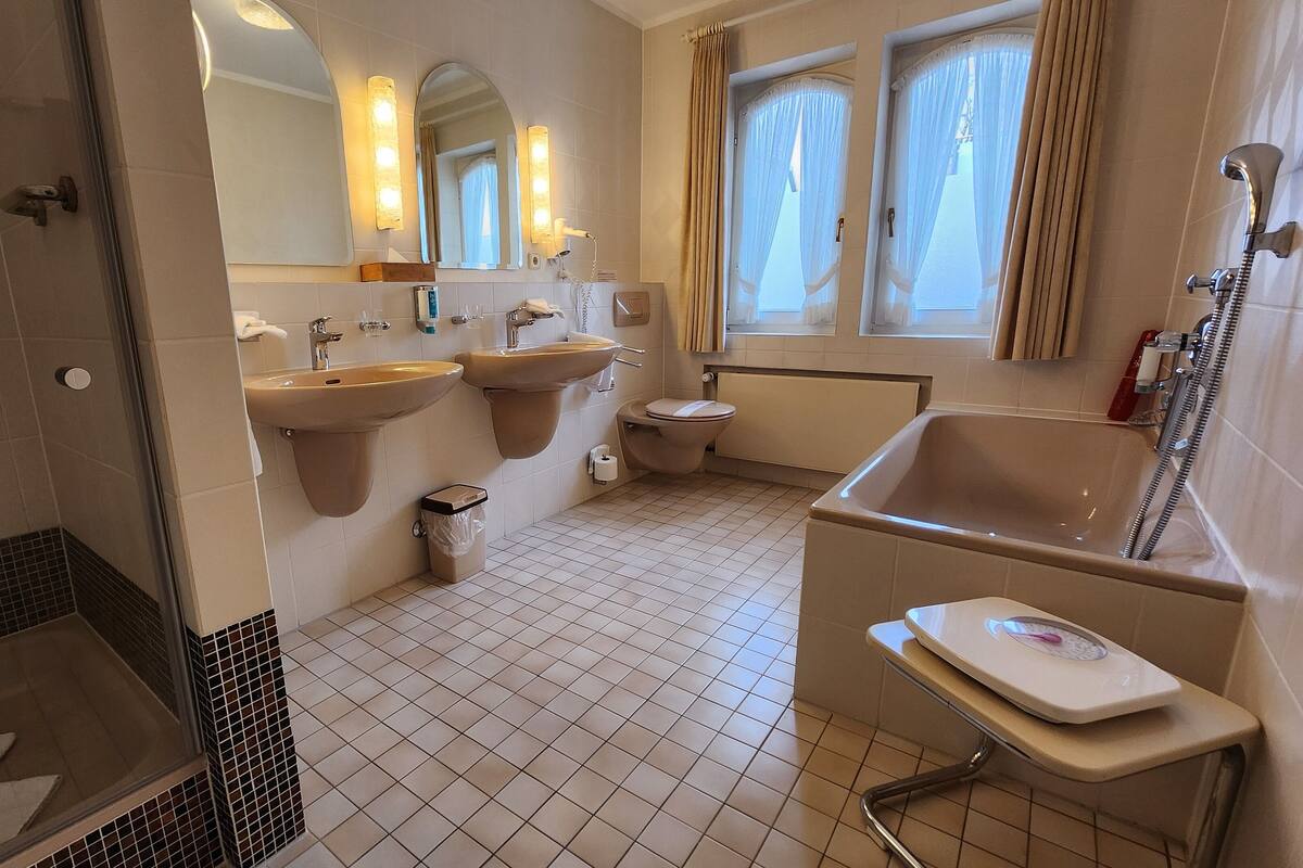 A modern bathroom with two sinks, a toilet, a bathtub, and a shower.