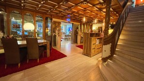 A spacious dining area with a wooden ceiling, a staircase, and a view into the living room. - Villa am Park (Bad Zwischenahn)