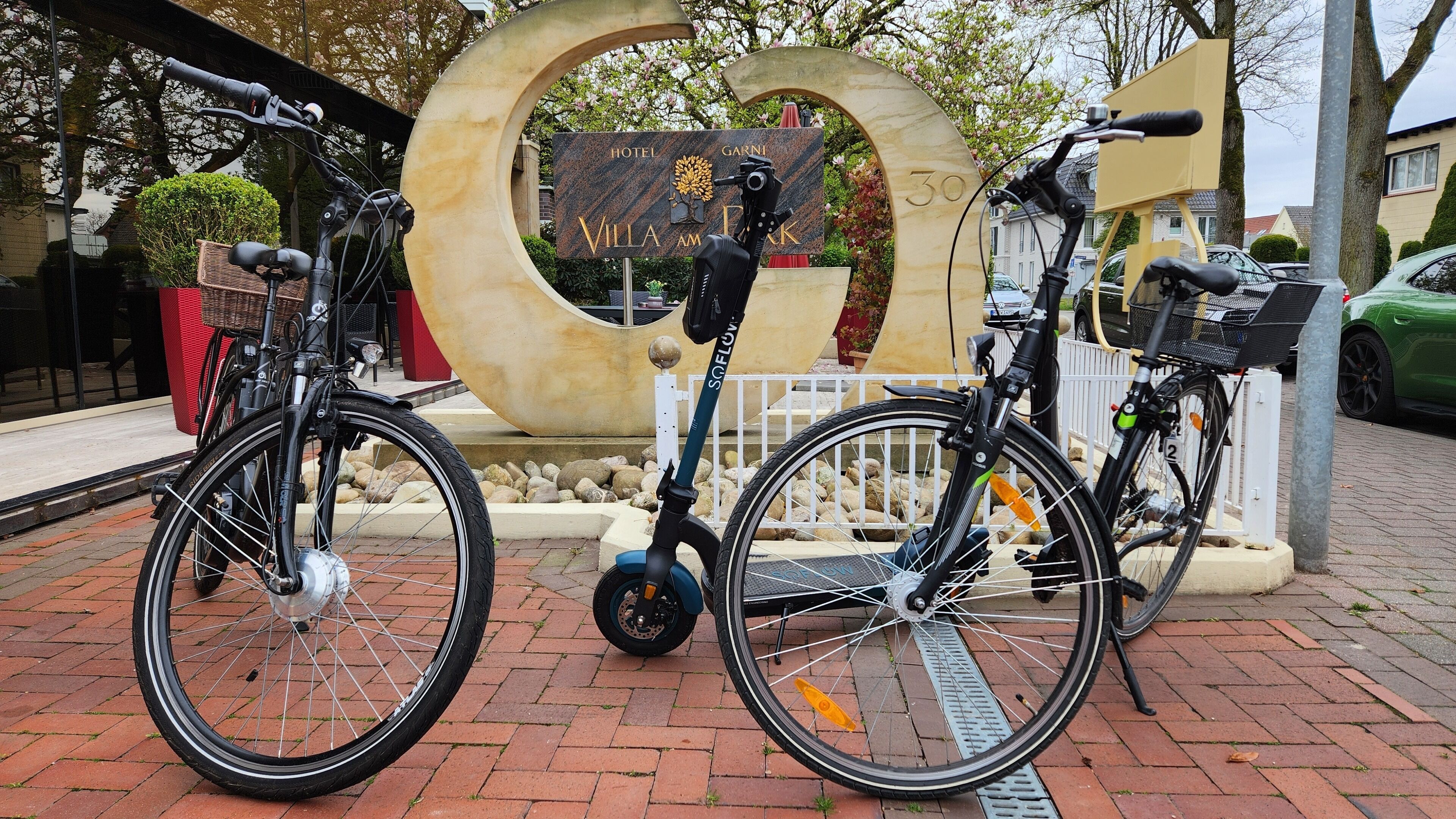 Dos bicicletas estacionadas frente a la entrada de un hotel con un gran letrero circular.