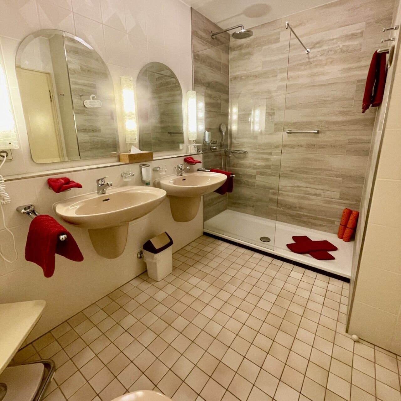 Un baño con dos lavamanos, una ducha y un espejo.