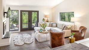 A modern living room with a white sofa, brown leather armchair, and a coffee table with decorative items. - Exquisite Group Retreat, 15-min to Downtown Boulder (Boulder)