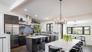 A modern kitchen with a central island, stainless steel appliances, and black bar stools. - Exquisite Group Retreat, 15-min to Downtown Boulder (Boulder)