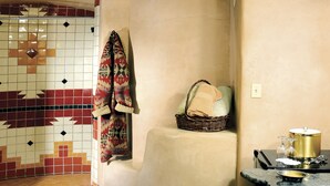 Een badkamer met een betegelde vloer, een wastafel met een goudkleurige kom en een mand met handdoeken.