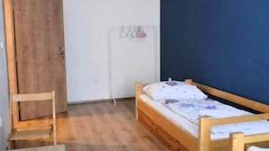 Una habitación con una cama de madera, una silla de madera, una mesita pequeña y un armario.