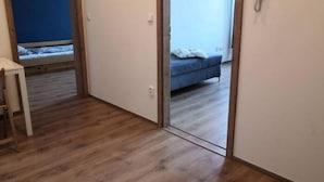 Una habitación con piso de madera, una cama con colchón azul y una mesita de noche.