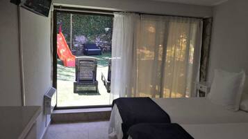 Quarto de hotel com cama, uma cadeira e vista para um escorrega e área externa.