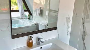 Une salle de bain avec un grand miroir, un lavabo blanc et des meubles en bois foncé.