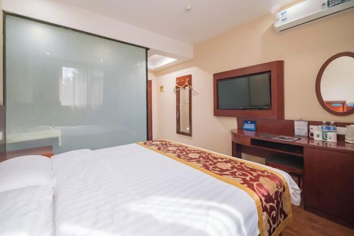 Habitación de hotel con cama, televisión, escritorio y espejo.