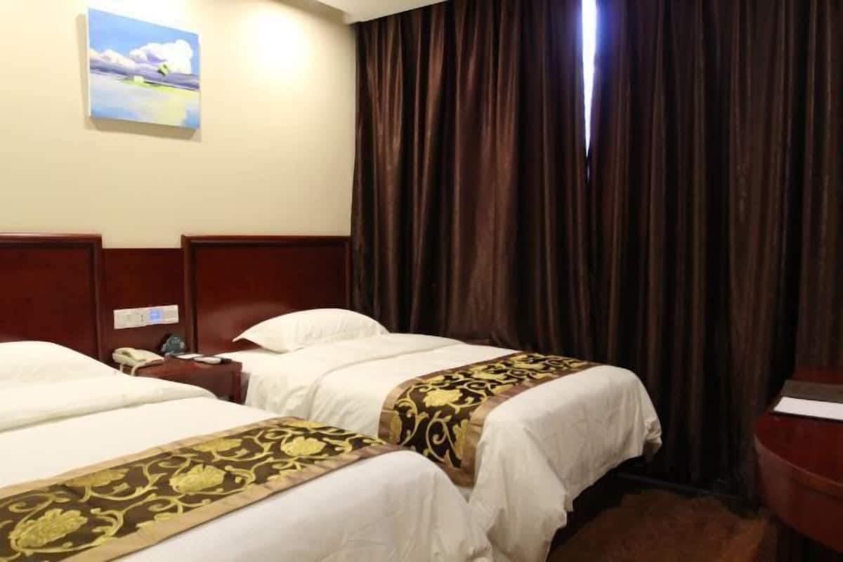 Habitación de hotel con dos camas, una mesita de noche, un cuadro y un ventanal con cortinas.