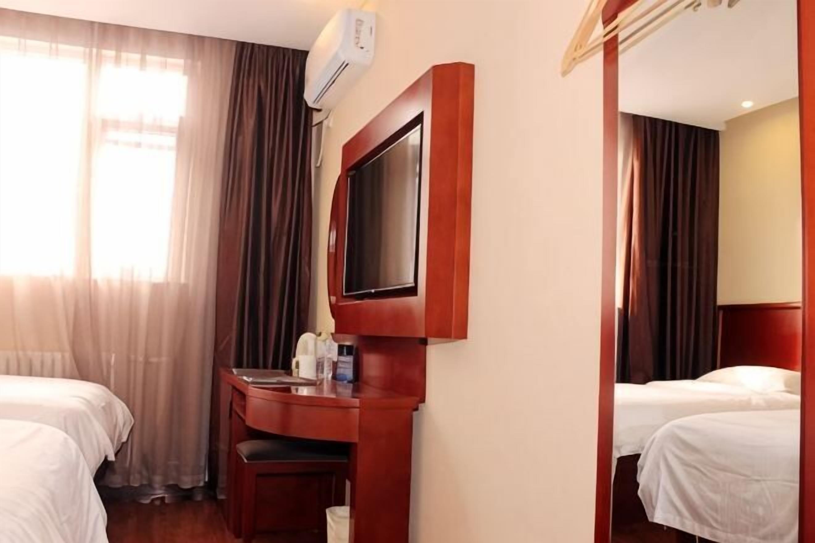 A hotel room with two beds, a desk with a chair, a TV, and a mirror.