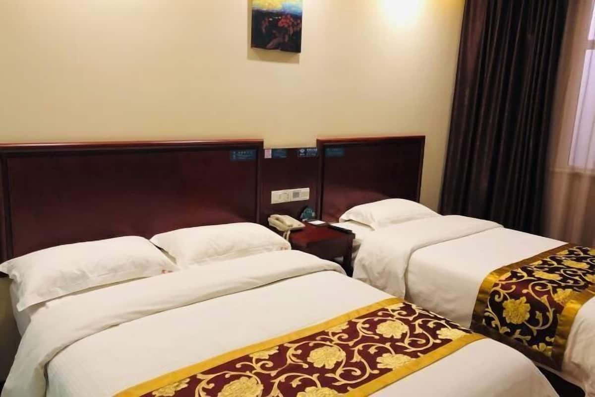 Una habitación de hotel con dos camas, una mesita de noche con teléfono y un cuadro en la pared.