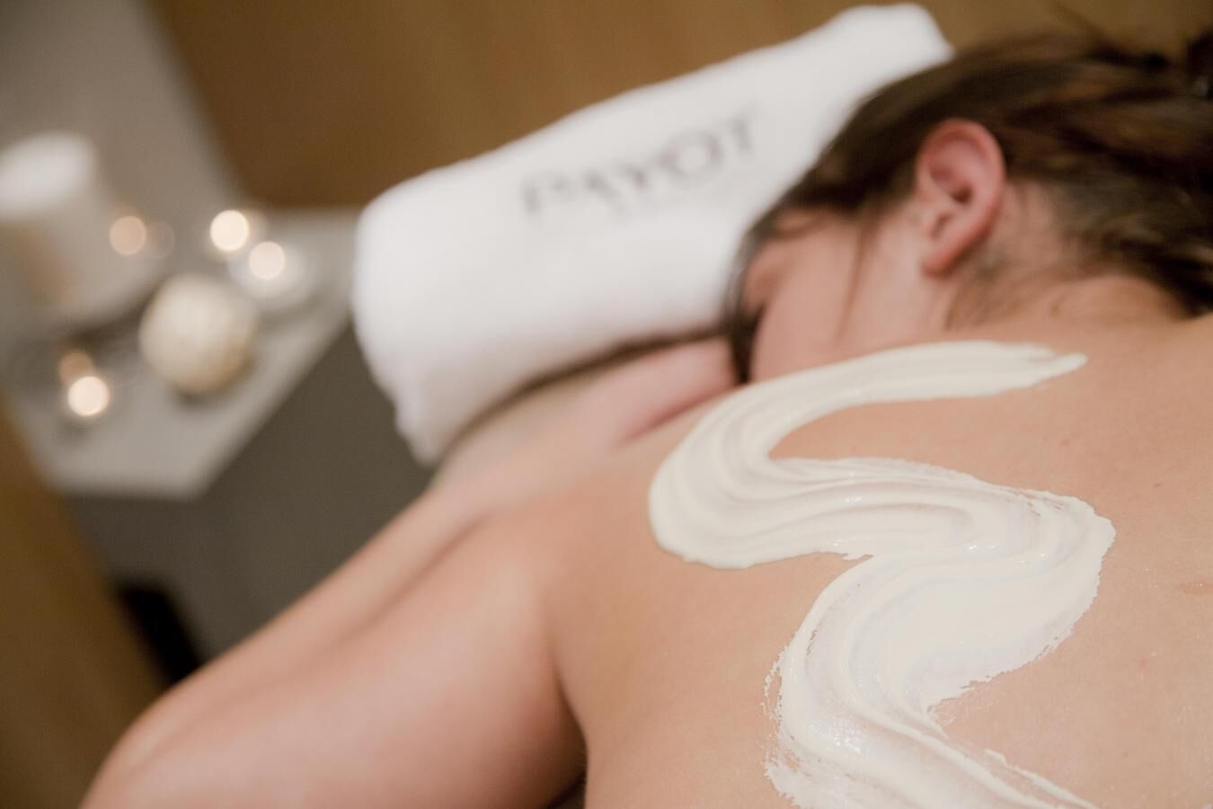Une personne reçoit un massage, une serviette portant l'inscription « PAYOT » étant placée sur sa tête.