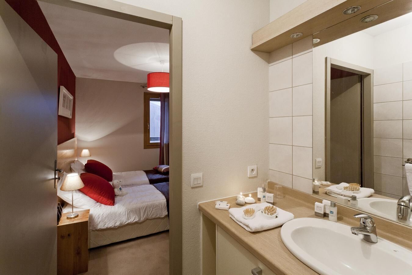 Une chambre d’hôtel comprenant un lit, une table de chevet, une lampe et une salle de bain avec un lavabo et un miroir.