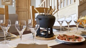 A dining table set with wine glasses, a black pot with wooden utensils, and a plate of food. - Ski-in/ski-out & foot of the slopes, swimming pool, balcony, tv, ski locker, 49-56m² (Sainte-Foy-Tarentaise)