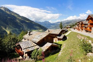A mountain lodge with stone roofs, wooden balconies, and a view of the surrounding mountains.