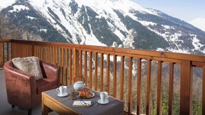 A balcony with a leather chair, a small table with a teapot, cups, and a book. - Ski-in/ski-out & foot of the slopes, swimming pool, balcony, tv, ski locker, 49-56m² (Sainte-Foy-Tarentaise)