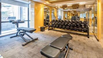 A gym with benches, dumbbells, and exercise equipment.
