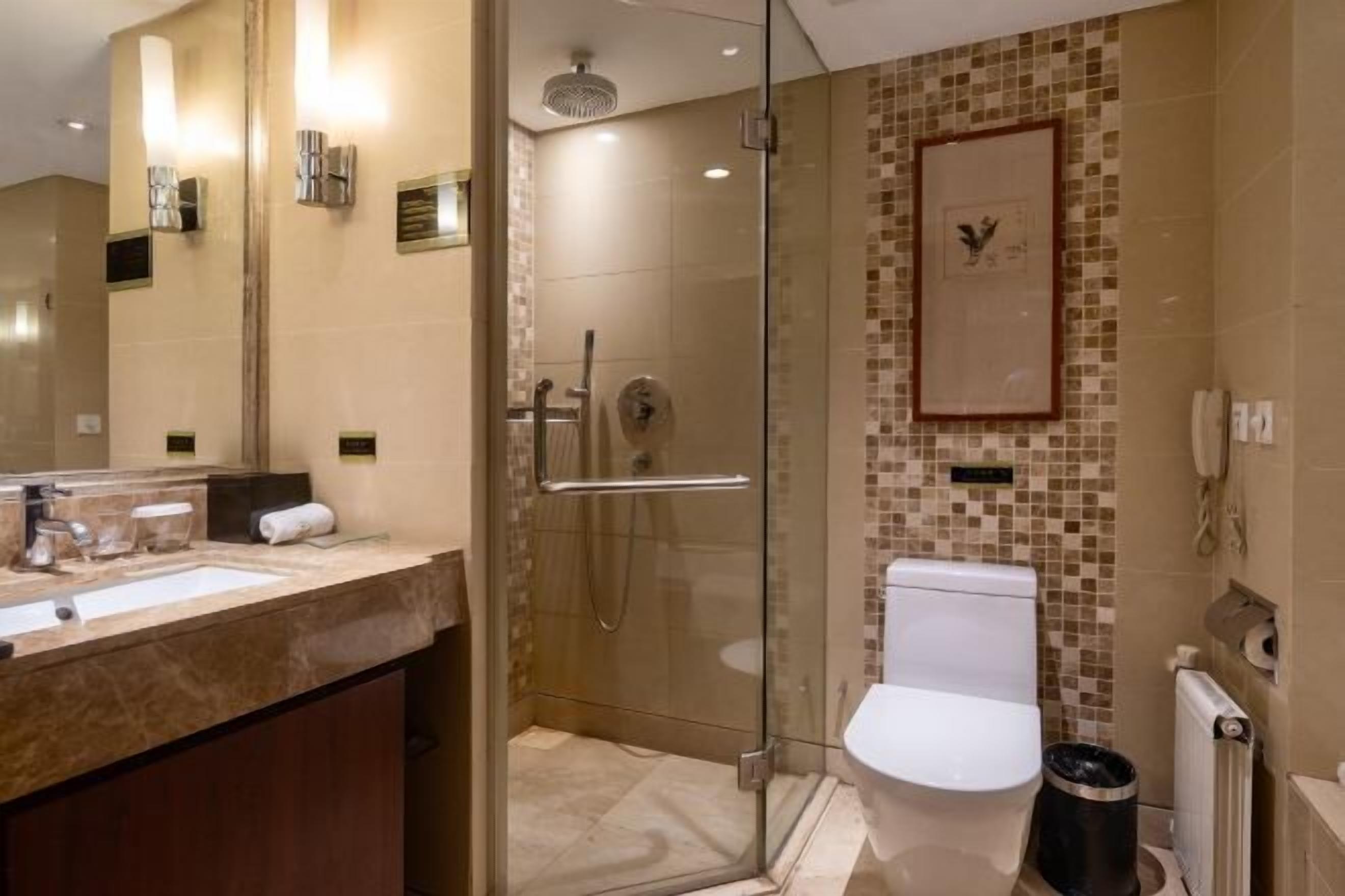 A modern bathroom with a glass-enclosed shower, a marble sink, and a toilet.