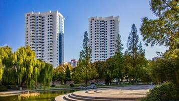 A park with a circular water feature and two tall buildings in the background.
