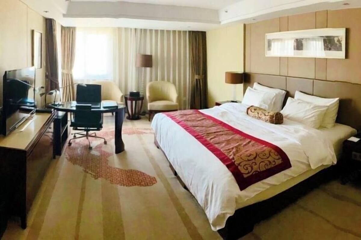 Ein Hotelzimmer mit Bett, Schreibtisch mit Stuhl, Fernseher und Lampe.