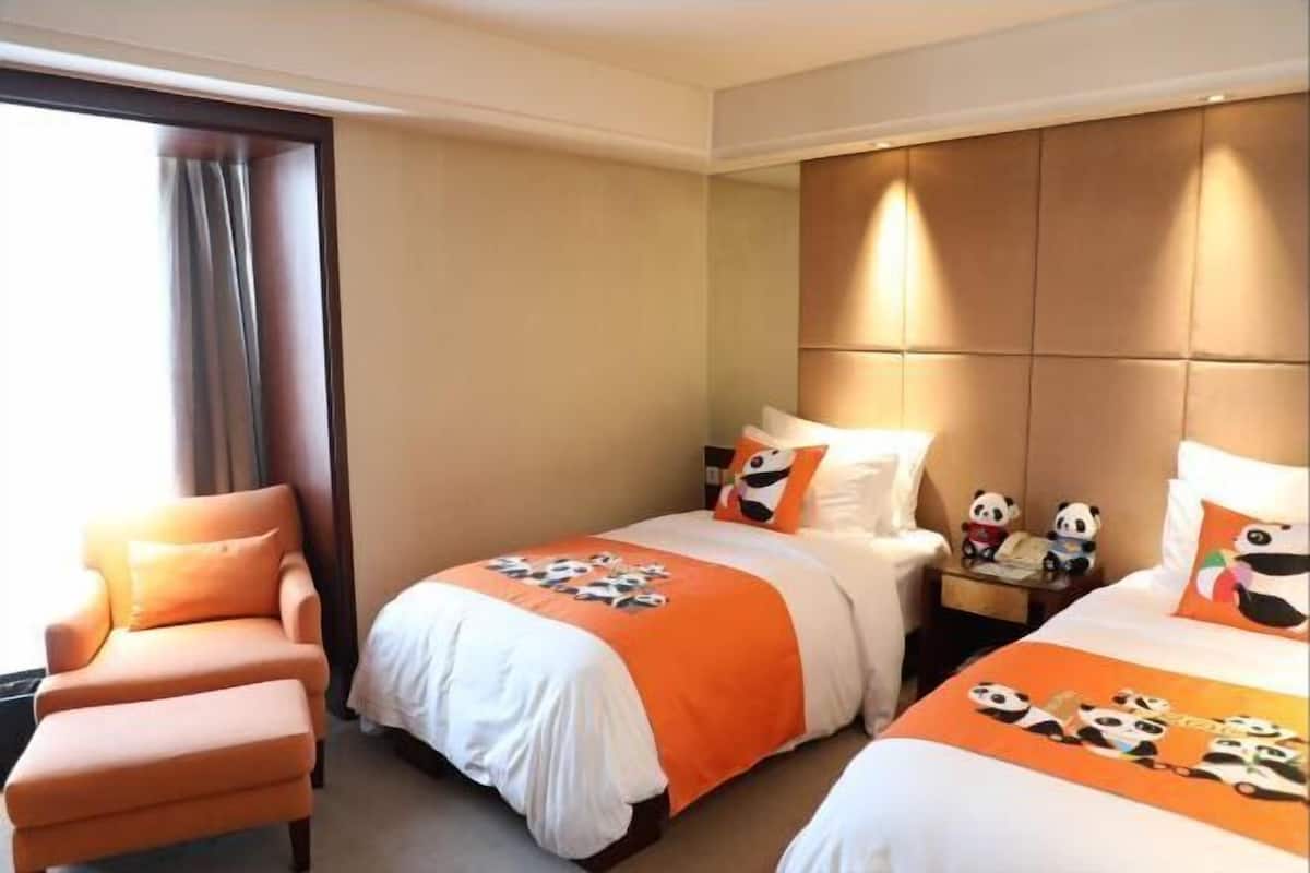 Ein Hotelzimmer mit zwei Betten, einer Couch und einem Nachttisch mit Panda-Figuren.