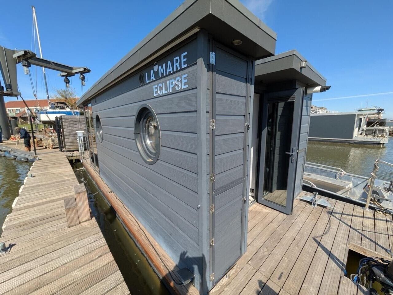 Un barco atracado llamado 'La Mare Eclipse' con una pequeña estructura tipo cabaña, una ventana y una puerta.