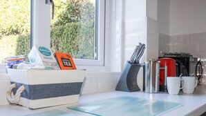 A kitchen counter with a basket containing tea bags, a coffee maker, and a knife block. - Pennine (Truro)
