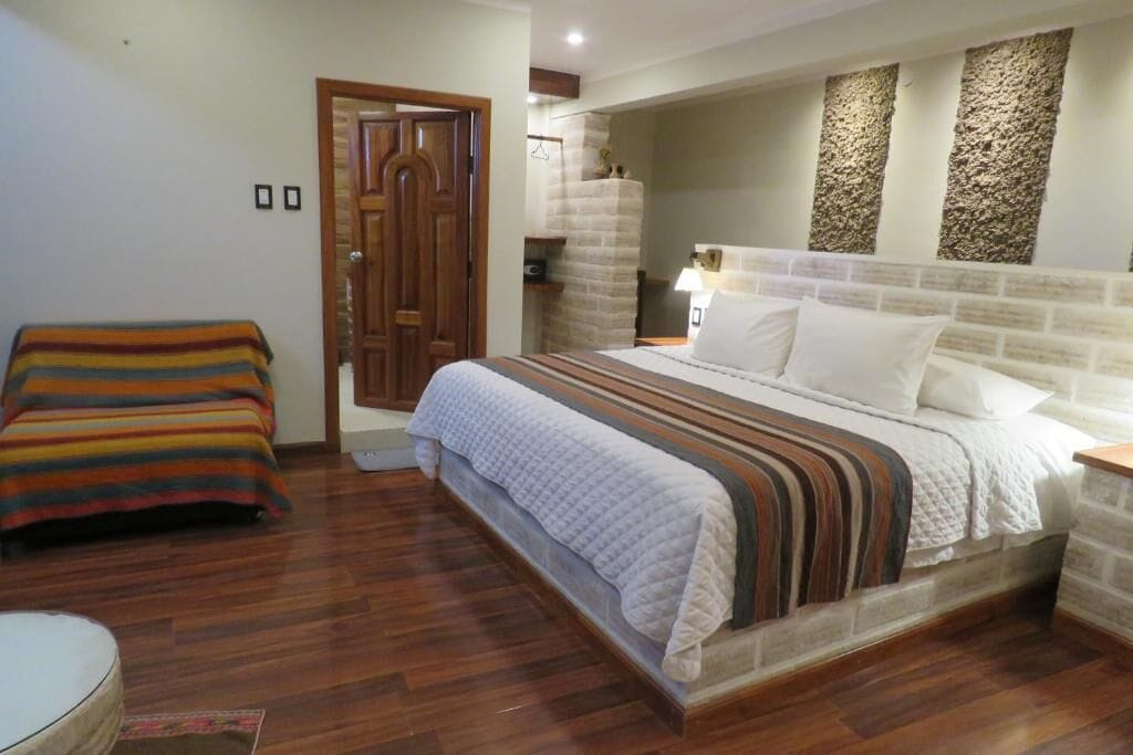 Une chambre à coucher avec un lit, un banc et une porte.