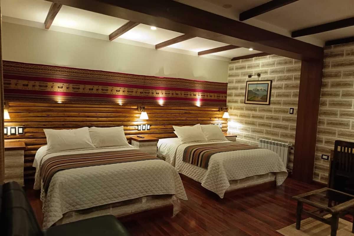 A hotel room with two beds, wooden headboard, brick-patterned walls, and a fireplace.