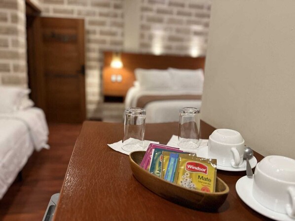 Habitación de hotel con una mesa de madera dispuesta para el desayuno, que incluye una bandeja con un sobre de té Windsor Mate, una taza y una cuchara.