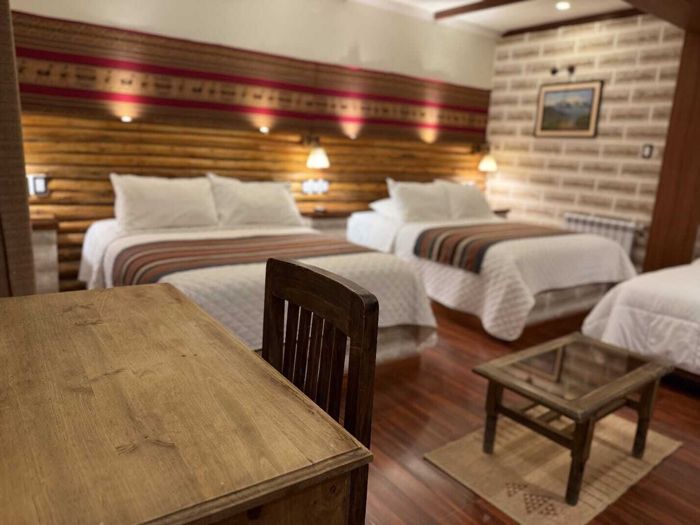 A hotel room with two beds, a wooden table, and a small wooden chair.