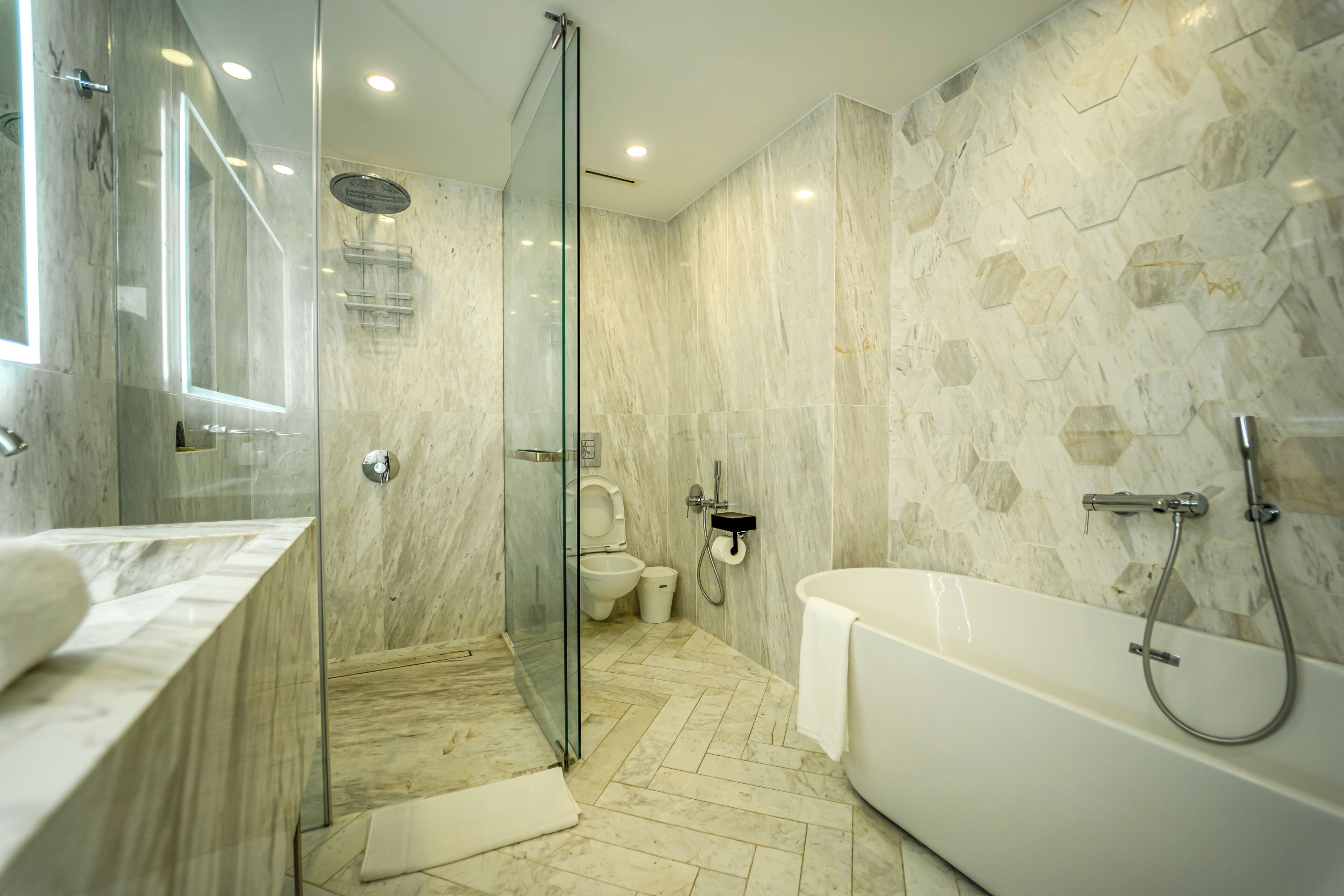 A modern bathroom with a glass-enclosed shower, a freestanding bathtub, and a toilet.