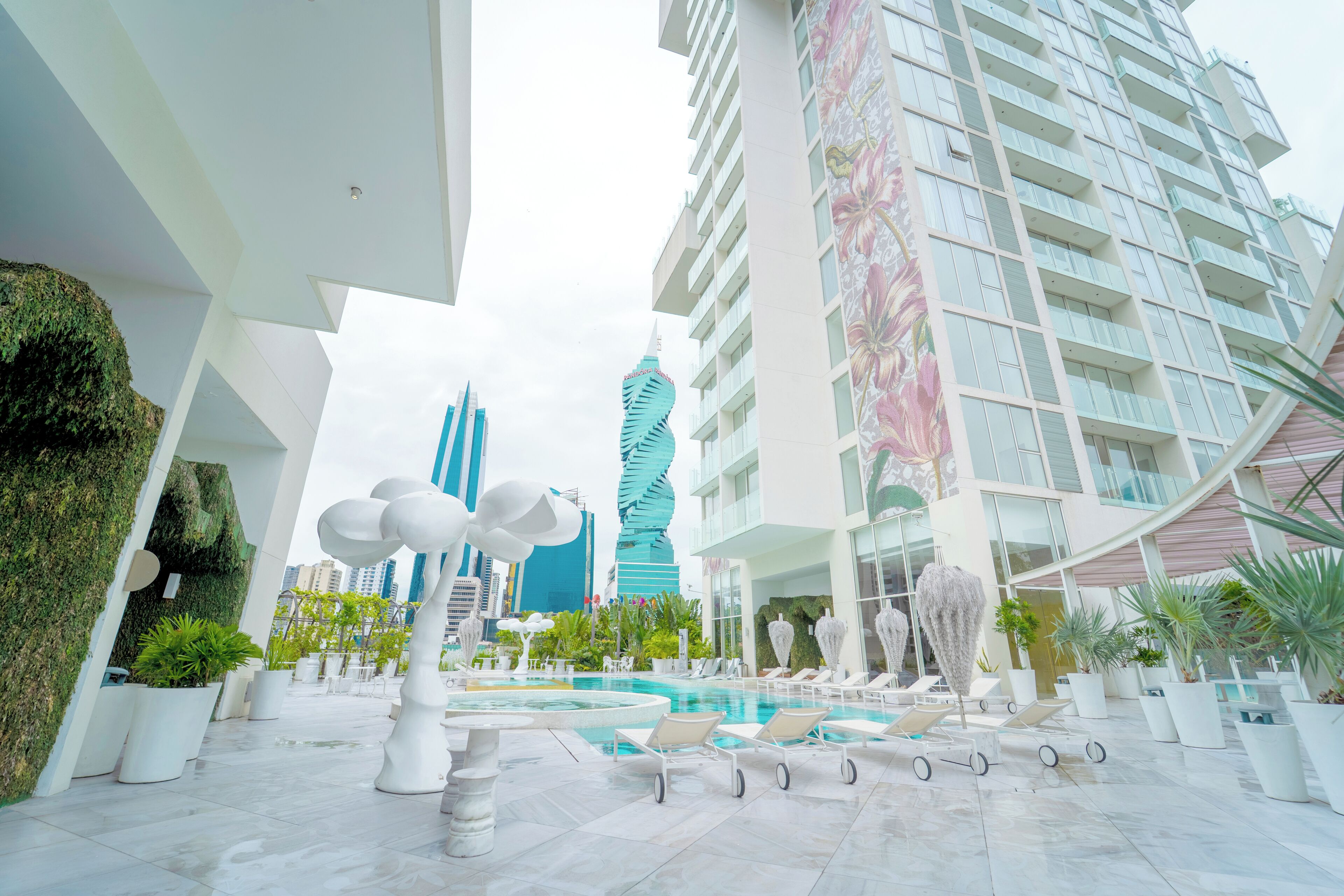 A modern hotel atrium with a pool, lounge chairs, and potted plants.