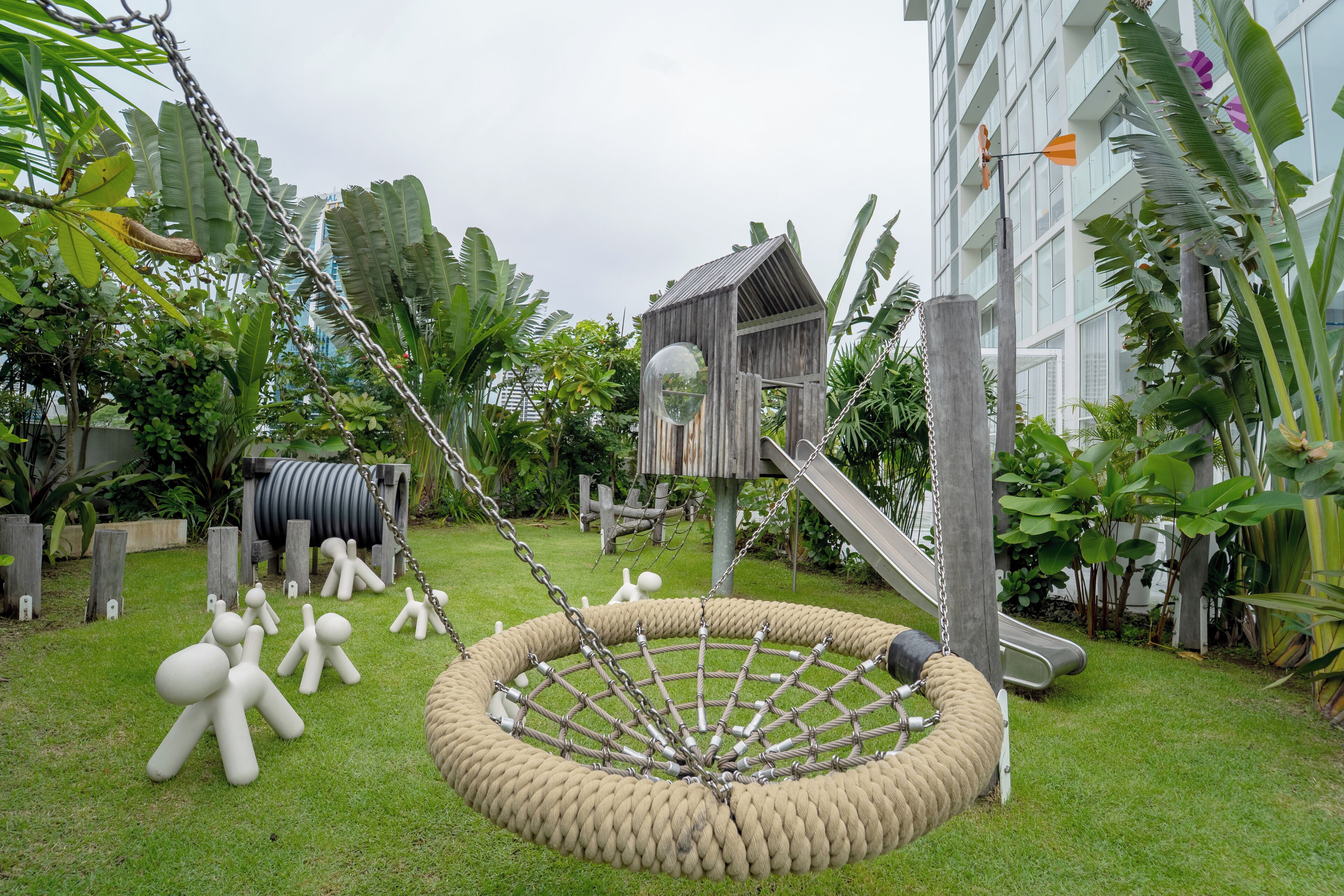 A playground with a rope swing, a wooden playhouse, and a slide.
