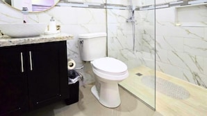 A modern bathroom with a marble backsplash, a white toilet, a black cabinet, and a glass-enclosed shower area. - Amber Glades (Kingston)