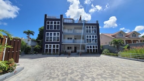 A multi-story building with a modern architectural design, featuring a central courtyard with a paved walkway. - Amber Glades (Kingston)