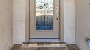 A front door with a glass panel and a metal gate, set in a beige wall with a stone-tiled entrance. - Westside spot near the Outlet Mall and Providence Hospital, with easy I-10 acces (El Paso)