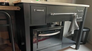Une petite cuisine équipée d’un four encastré et d’un petit réfrigérateur.