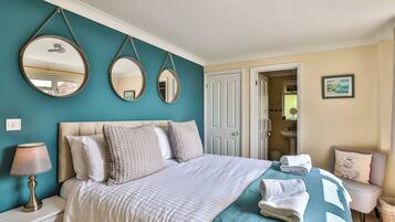 A bedroom with a bed, two wall mirrors, a bedside lamp, a door, and a view of the bathroom.