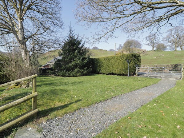 A rural pathway leading to a gated entrance, surrounded by a well-maintained lawn and a hedge. - Old Ty'n Y Wern (Bala)